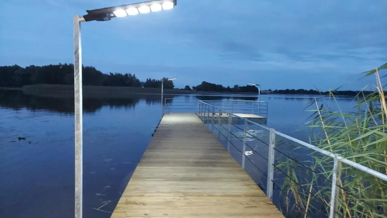 Drewniany pomost nad jeziorem, oświetlony lampami, zaprasza do wieczornego spaceru. Czy pomost nad jeziorem może być prywatny?
