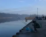 Wędkarz siedzi na krześle przy spokojnym łowisku garbów, czekając na branie.