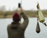 Wędkarz przygotowuje zestaw zig rig. Widać ciężarek i pływak, gotowe do zarzucenia.