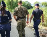 Trzech funkcjonariuszy, w tym policjantka, patroluje teren nad wodą. To może być straz rybacka w akcji.