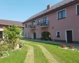 Urokliwe łowisko Trzeboszowice. Różowy budynek z balkonami, zielony ogród i ścieżka z kostki brukowej.