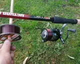 Wędka method feeder z kołowrotkiem i nową żyłką na trawie. Idealna żyłka do method feeder to podstawa udanego połowu.