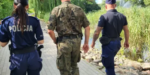 Trzech funkcjonariuszy, w tym policjantka, patroluje teren nad wodą. To może być straz rybacka w akcji.