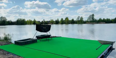 Zielone łowisko garbów u baby, gotowe na wielkie połowy. W tle spokojna tafla jeziora i błękitne niebo z chmurami.