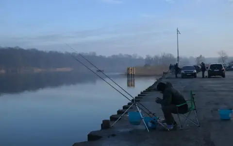 Wędkarz siedzi na krześle przy spokojnym łowisku garbów, czekając na branie.