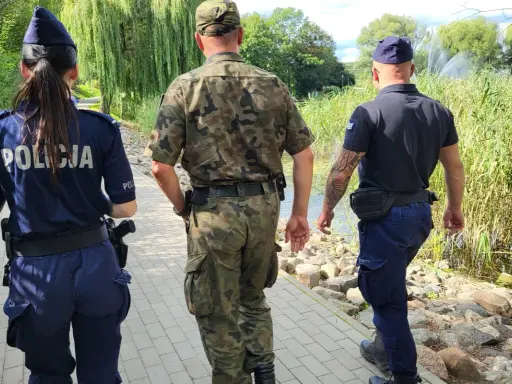 Trzech funkcjonariuszy, w tym policjantka, patroluje teren nad wodą. To może być straz rybacka w akcji.