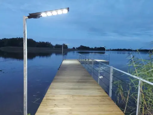 Drewniany pomost nad jeziorem, oświetlony lampami, zaprasza do wieczornego spaceru. Czy pomost nad jeziorem może być prywatny?