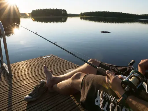 Relaks na pomoście nad jeziorem Wysoka. Słońce zachodzi, a wędkarz czeka na branie.