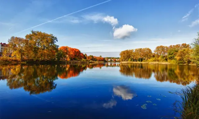 Jesioro Skarlińskie w jesiennej odsłonie. Kolorowe drzewa odbijają się w spokojnej tafli wody.