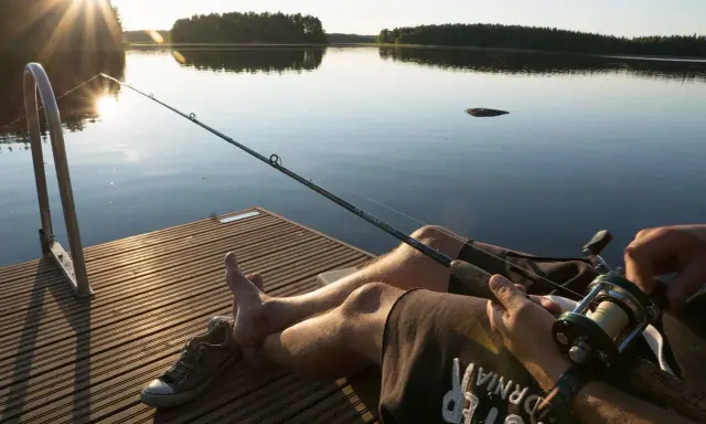 Relaks na pomoście nad jeziorem Wysoka. Słońce zachodzi, a wędkarz czeka na branie.