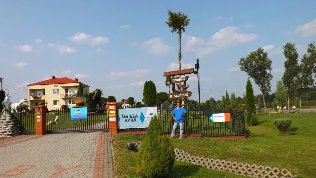 Łowisko komercyjne w Słupowie. Mężczyzna w niebieskiej koszulce stoi przy bramie.